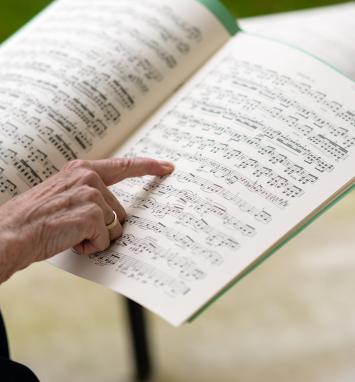An older woman points at sheet music